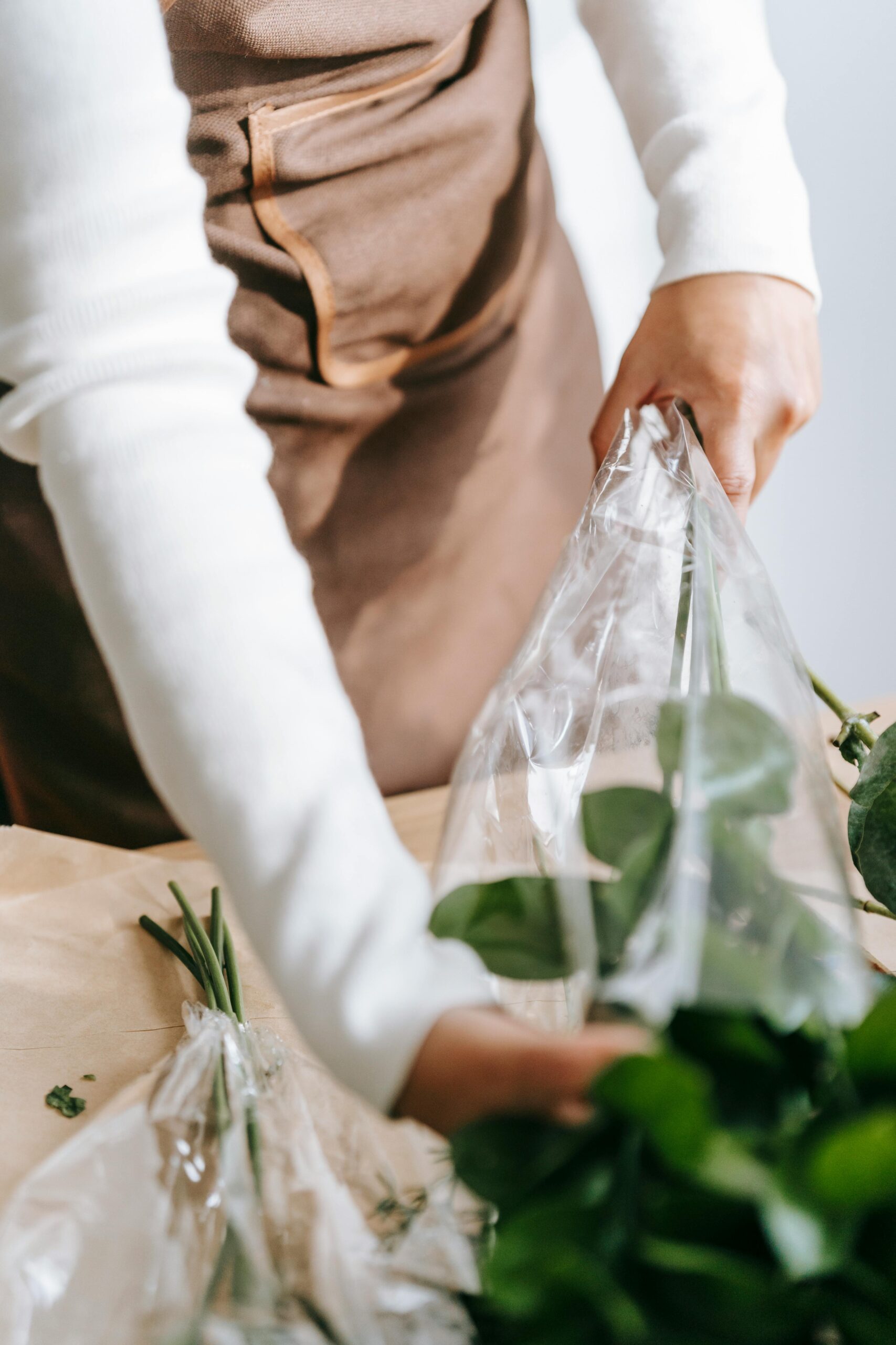 Florist wrapping fresh bouquet in plastic at a market, highlighting floral business ambiance. Business Planning - We support and strengthen the key elements of your business to build a durable enterprise that is positioned for growth, scale or exit. 